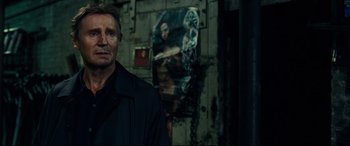 Movie still from “Widows” (2018), directed by Steve McQueen – A man standing in front of a poster of a woman; Close Up shot, Over the shoulder angle