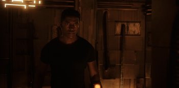 Movie still from “Another Life” (2019), created by Aaron Martin – A man standing in the dark holding a candle; Medium shot, Low angle