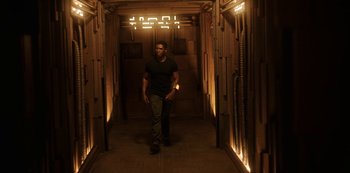 Movie still from “Another Life” (2019), created by Aaron Martin – A man walking down a hallway in a building; Wide shot, High angle