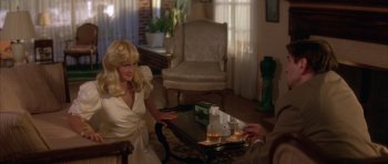 Movie still from “Wild at Heart” (1990), directed by David Lynch – A woman sitting at a table in a living room; Medium shot, High angle