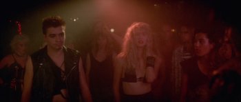 Movie still from “Wild at Heart” (1990), directed by David Lynch – A group of people standing in a dark room; Medium shot, Over the shoulder angle