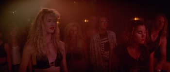 Movie still from “Wild at Heart” (1990), directed by David Lynch – A group of people standing in a dark room; Medium shot, Over the shoulder angle
