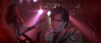 Movie still from “Wild at Heart” (1990), directed by David Lynch – A man is singing into a microphone in front of a crowd; Close Up shot, Low angle