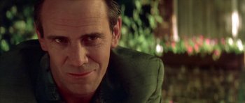 Movie still from “Wild at Heart” (1990), directed by David Lynch – A man smiling for the camera; Close Up shot, Over the shoulder angle