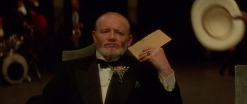 Movie still from “Wild at Heart” (1990), directed by David Lynch – An older man in a tuxedo holding a piece of paper in his hand; Close Up shot, Low angle