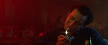 Movie still from “Wild at Heart” (1990), directed by David Lynch – A man is lighting a cigarette in a dark room; Close Up shot, Low angle
