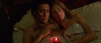 Movie still from “Wild at Heart” (1990), directed by David Lynch – A man and a woman laying in a bed with a candle; Close Up shot, Overhead angle