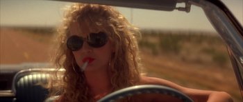 Movie still from “Wild at Heart” (1990), directed by David Lynch – A woman with a cigarette in her mouth driving a car; Close Up shot, Low angle