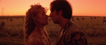 Movie still from “Wild at Heart” (1990), directed by David Lynch – A man and a woman kissing in a field at sunset; Close Up shot, Overhead angle