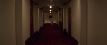 Movie still from “Wild at Heart” (1990), directed by David Lynch – A person walking down a long hallway in a hotel room; Extreme Wide shot, High angle