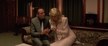 Movie still from “Wild at Heart” (1990), directed by David Lynch – A man and a woman sitting next to each other on a couch; Medium shot, Low angle