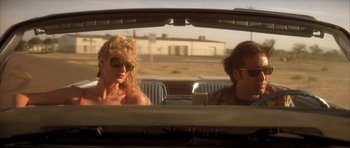 Movie still from “Wild at Heart” (1990), directed by David Lynch – A woman and a man sitting in the back of a car; Medium shot, Low angle
