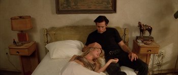 Movie still from “Wild at Heart” (1990), directed by David Lynch – A man and a woman laying in a bed together; Medium shot, Low angle