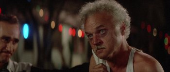 Movie still from “Wild at Heart” (1990), directed by David Lynch – An older man with white hair looking at the camera; Close Up shot, Low angle