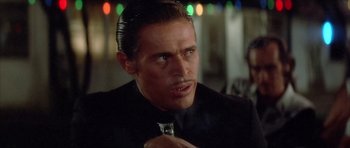 Movie still from “Wild at Heart” (1990), directed by David Lynch – A person wearing a suit and tie with lights in the background; Close Up shot, Low angle