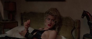 Movie still from “Wild at Heart” (1990), directed by David Lynch – A woman in a black top laying on a bed; Close Up shot, Low angle