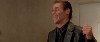 Movie still from “Wild at Heart” (1990), directed by David Lynch – A person wearing a suit and smiling; Close Up shot, Low angle