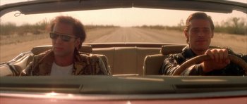 Movie still from “Wild at Heart” (1990), directed by David Lynch – Two people sitting in the back seat of a car; Close Up shot, Low angle