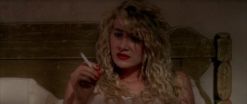 Movie still from “Wild at Heart” (1990), directed by David Lynch – A woman holding a cigarette in her hand; Close Up shot, High angle