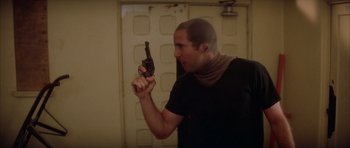 Movie still from “Wild at Heart” (1990), directed by David Lynch – A man holding a gun up to his face; Close Up shot, Over the shoulder angle