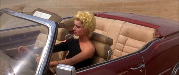 Movie still from “Wild at Heart” (1990), directed by David Lynch – A woman sitting in the driver's seat of a car; Medium shot, High angle