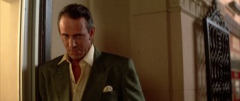 Movie still from “Wild at Heart” (1990), directed by David Lynch – A man wearing a suit and tie standing in a room; Close Up shot, Over the shoulder angle
