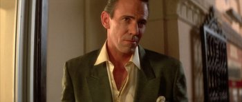 Movie still from “Wild at Heart” (1990), directed by David Lynch – A person wearing a suit and tie; Close Up shot, Low angle