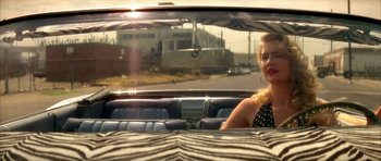 Movie still from “Wild at Heart” (1990), directed by David Lynch – A woman sitting in the back seat of a car; Medium shot, Over the shoulder angle