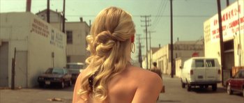 Movie still from “Wild at Heart” (1990), directed by David Lynch – A woman with long blonde hair is standing on the side of the street; Close Up shot, Over the shoulder angle