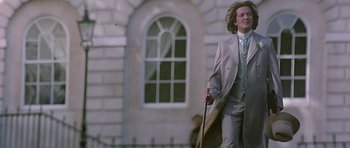 Movie still from “Wilde” (1997), directed by Brian Gilbert – A man in a suit and tie holding an umbrella; Medium shot, Low angle