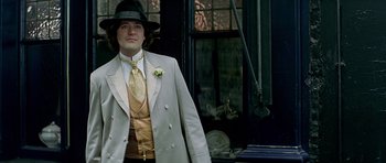 Movie still from “Wilde” (1997), directed by Brian Gilbert – A man in a suit and hat standing in front of a building; Medium shot, Low angle