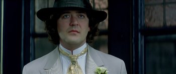 Movie still from “Wilde” (1997), directed by Brian Gilbert – A person wearing a suit and hat; Close Up shot, Low angle