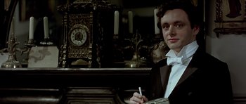 Movie still from “Wilde” (1997), directed by Brian Gilbert – A man in a suit and bow tie holding a cigarette in his hand; Close Up shot, High angle