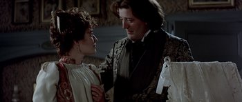 Movie still from “Wilde” (1997), directed by Brian Gilbert – A man and a woman standing next to each other in a room; Medium shot, Over the shoulder angle