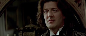 Movie still from “Wilde” (1997), directed by Brian Gilbert – A person wearing a suit and tie; Close Up shot, Low angle