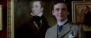 Movie still from “Wilde” (1997), directed by Brian Gilbert – A man standing in front of a painting of a man; Close Up shot, Low angle