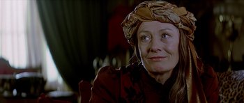 Movie still from “Wilde” (1997), directed by Brian Gilbert – An older woman wearing a head scarf and a red dress; Close Up shot, Over the shoulder angle