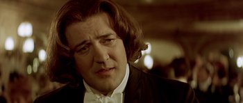 Movie still from “Wilde” (1997), directed by Brian Gilbert – A person wearing a suit and bow tie; Close Up shot, Over the shoulder angle