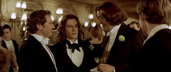 Movie still from “Wilde” (1997), directed by Brian Gilbert – A group of men in tuxedos standing next to each other; Medium shot, Over the shoulder angle