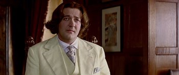 Movie still from “Wilde” (1997), directed by Brian Gilbert – A man in a white suit with long brown hair; Close Up shot, Over the shoulder angle