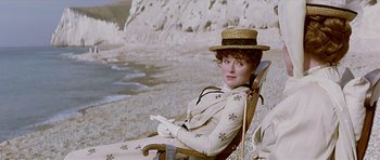 Movie still from “Wilde” (1997), directed by Brian Gilbert – A woman sitting in a chair on the beach; Medium shot, High angle