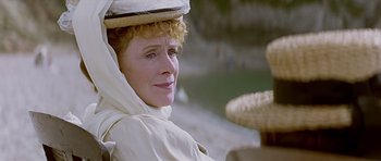 Movie still from “Wilde” (1997), directed by Brian Gilbert – An older woman wearing a straw hat sitting on a chair; Close Up shot, Low angle