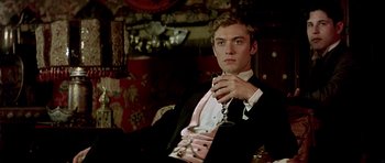 Movie still from “Wilde” (1997), directed by Brian Gilbert – A young man in a tuxedo holding a glass of wine; Medium shot, Low angle