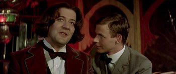 Movie still from “Wilde” (1997), directed by Brian Gilbert – Two men in suits and bow ties talking to each other; Close Up shot, Over the shoulder angle