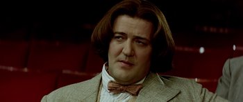 Movie still from “Wilde” (1997), directed by Brian Gilbert – A person wearing a suit and bow tie; Close Up shot, Over the shoulder angle