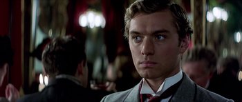 Movie still from “Wilde” (1997), directed by Brian Gilbert – A man in a suit and tie looking at the camera; Close Up shot, Over the shoulder angle