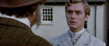 Movie still from “Wilde” (1997), directed by Brian Gilbert – A man in a suit and tie standing next to another man in front of a building; Close Up shot, Over the shoulder angle