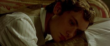 Movie still from “Wilde” (1997), directed by Brian Gilbert – A man laying on a bed with his head on a pillow; Close Up shot, High angle