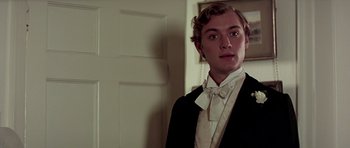 Movie still from “Wilde” (1997), directed by Brian Gilbert – A man in a suit and bow tie standing next to a door; Close Up shot, Low angle