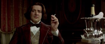 Movie still from “Wilde” (1997), directed by Brian Gilbert – A man holding a cigarette in his right hand; Close Up shot, Low angle